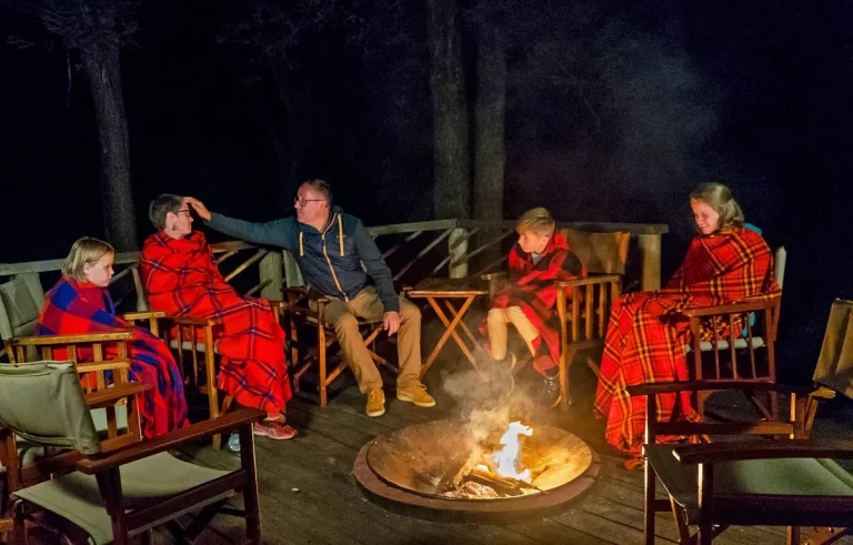 South africa safari hotels- a family on safari gathered around a camp fire