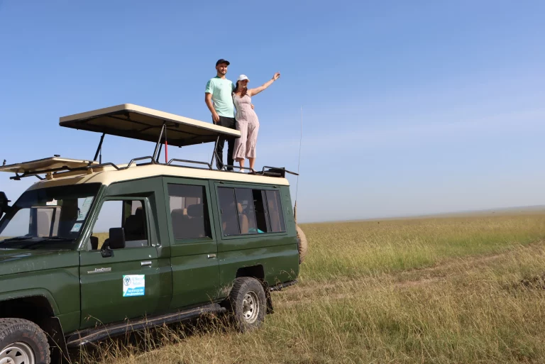 Nairobi day tours- tourists on a game drive pose for a pic while standing on top of our safari Landcruiser
