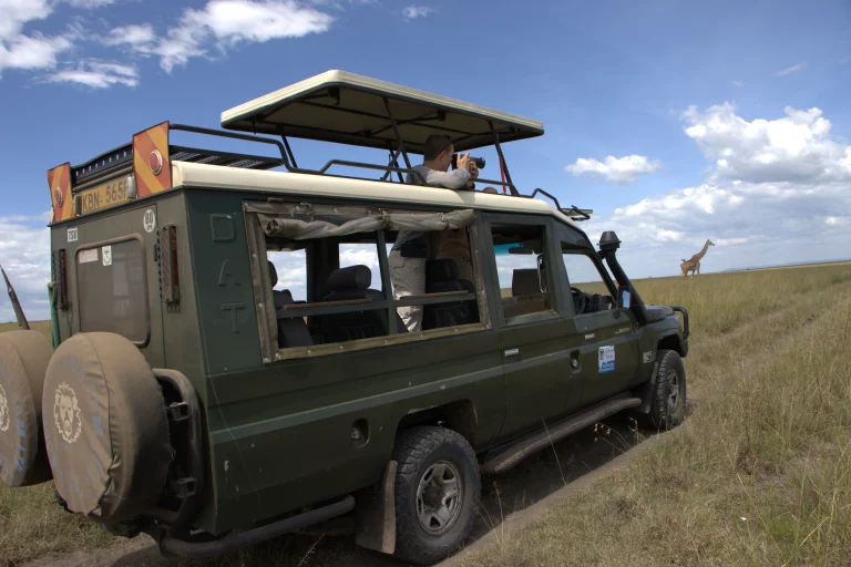 South Africa safari hotels- tourist inside safari van observes wildlife using binoculars