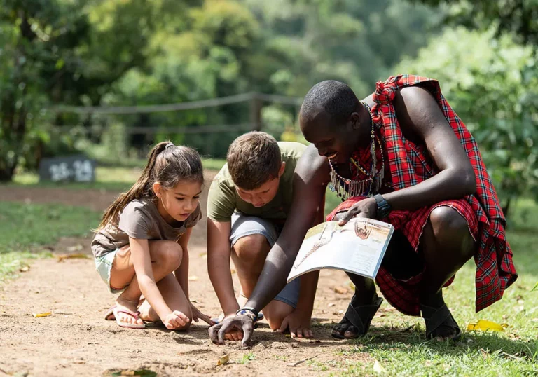 Tour safaris in Kenya- Masai Moran teaches two young tourists about animal tracking