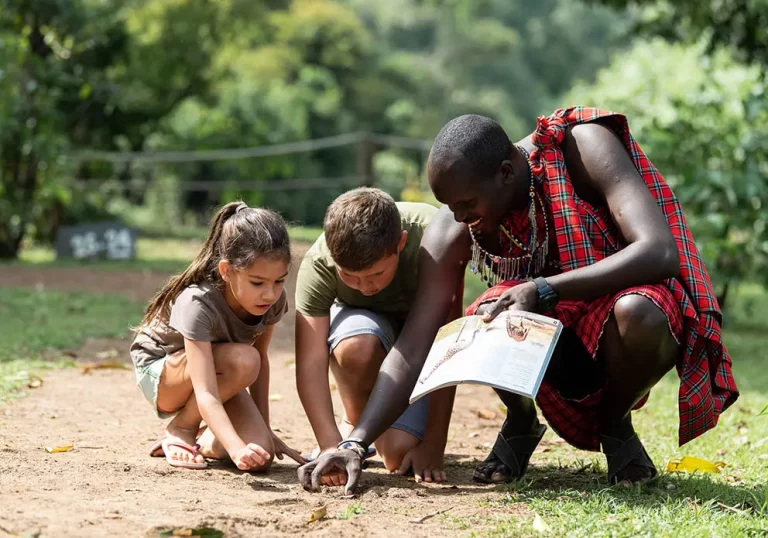 Tours to Kruger national park- a masai moran teaches two kids about tracking animals by their footsteps