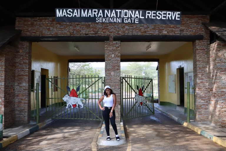 Safari vacation south africa-woman poses for a picture at masai mara entrance gate