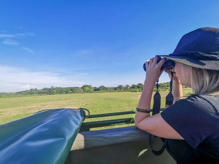 Best safari holidays- a tourist uses her binoculars to observe wildlife