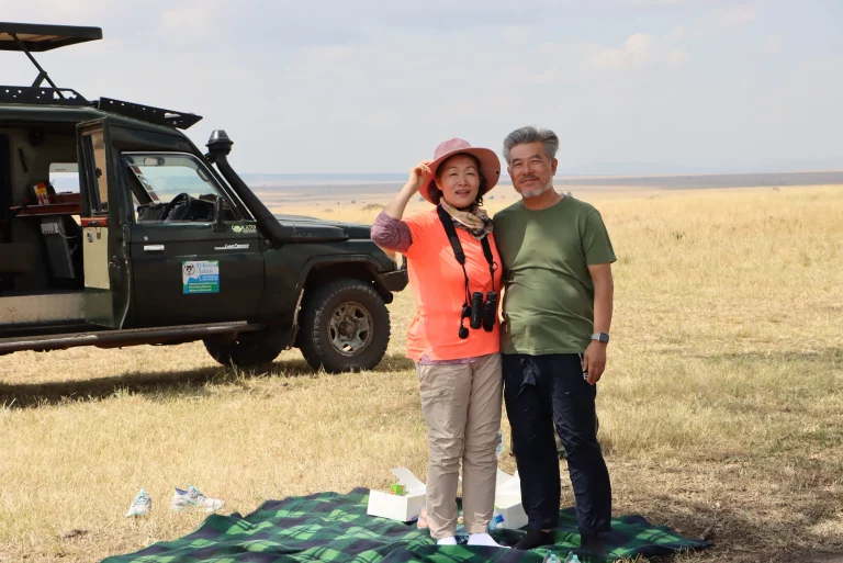 Hot holidays February- tourists on a game drive in the Mara pose for a photo in front of our safari Landcruiser