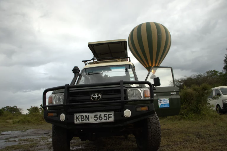 Safari lodges south Africa- a hot-air ballon floating on air behind a safari van parked in the mara national park