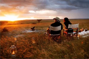 How to calculate the cost of safari in Kenya - a couple enjoying a sundowner in the wilderness