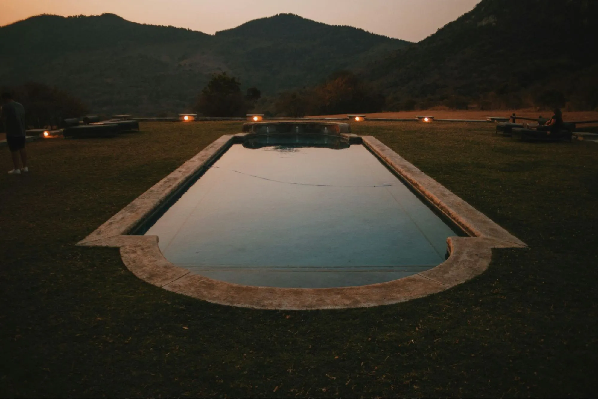 Discover tranquility at an African safari hotel with a pool amidst a picturesque field, embraced by breathtaking mountains